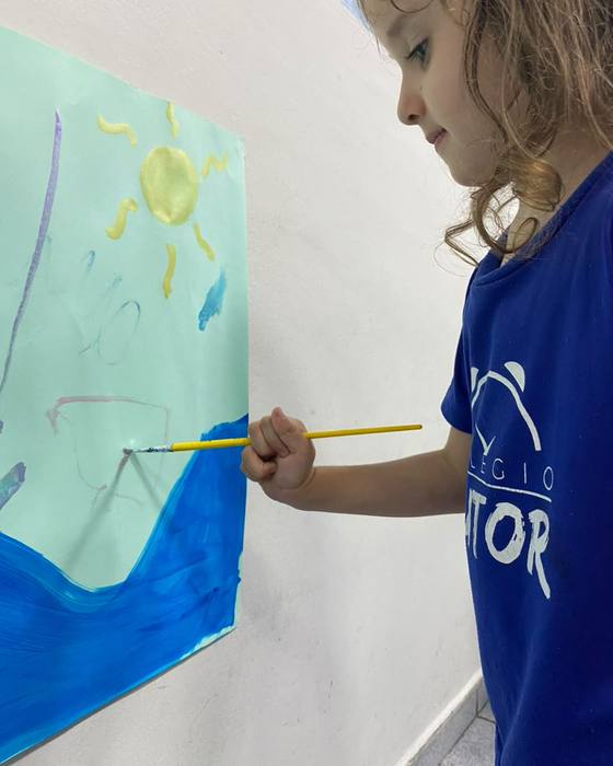 Aluna pintando um mural com pincel
