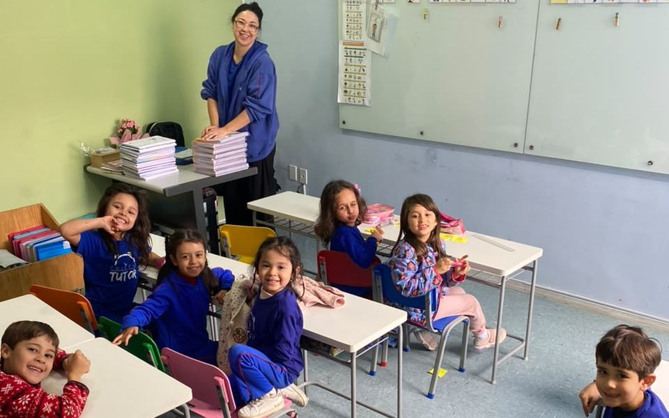 Alunos do Ensino Fundamental sorrindo em sala de aula com a professora